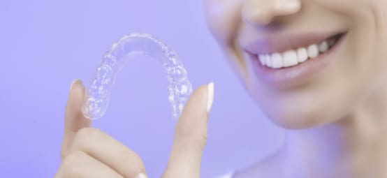 Lady Holding Invisalign Aligners in Her Hand